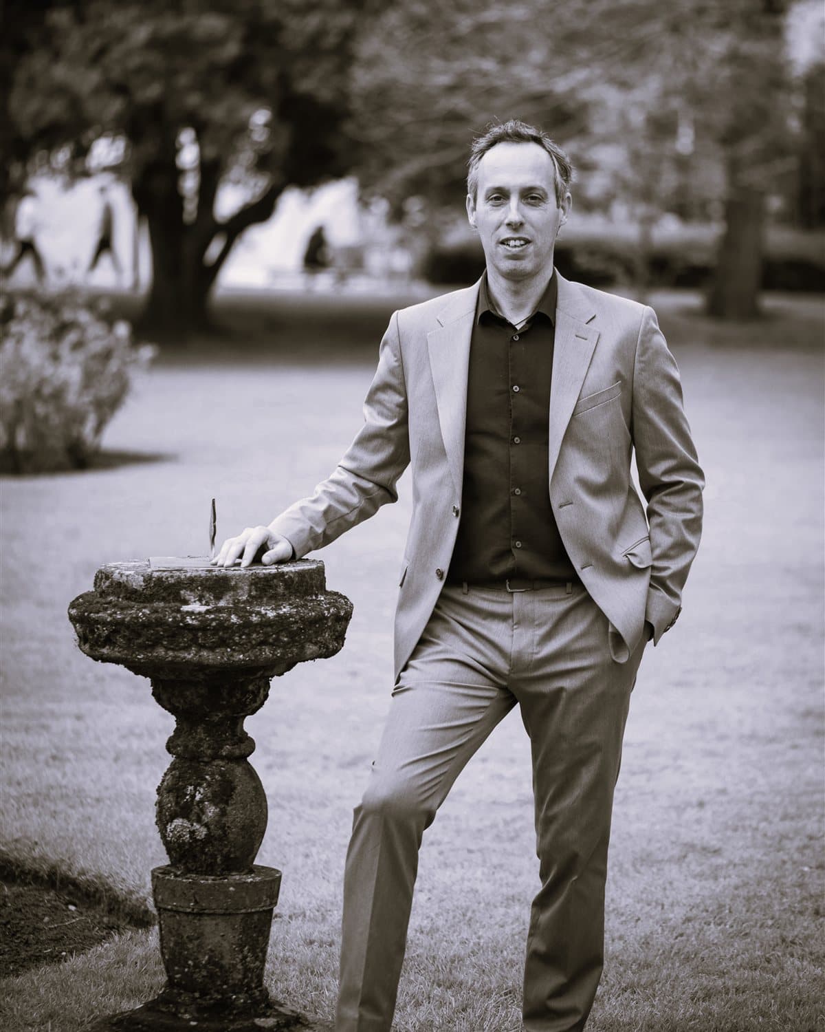 Jeff Gomez in a park, hand resting on a stone sundial
